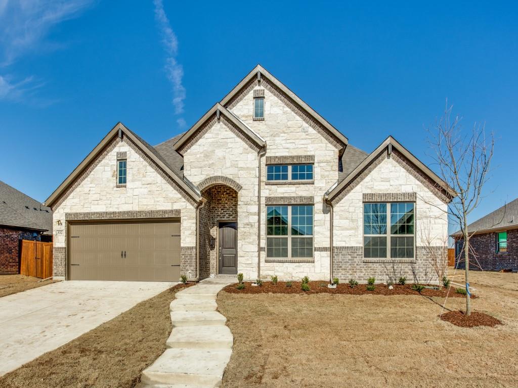 French country home with a garage, driveway, and stone siding