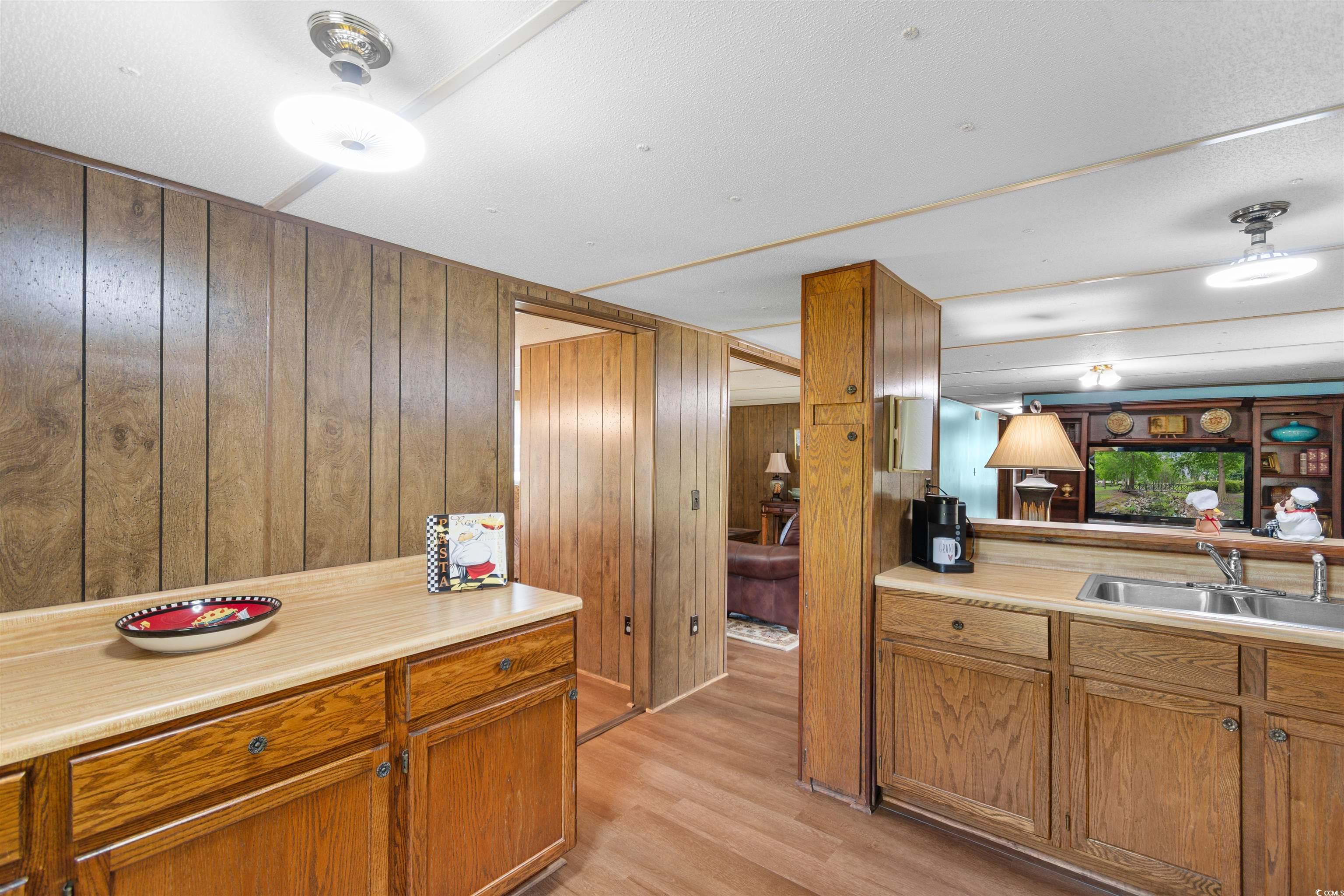 299 Williams Hill Road Hemingway, SC 29554 - Photo 11 of 40 Kitchen with wooden walls, light countertops, light wood finished floors, and brown cabinetry