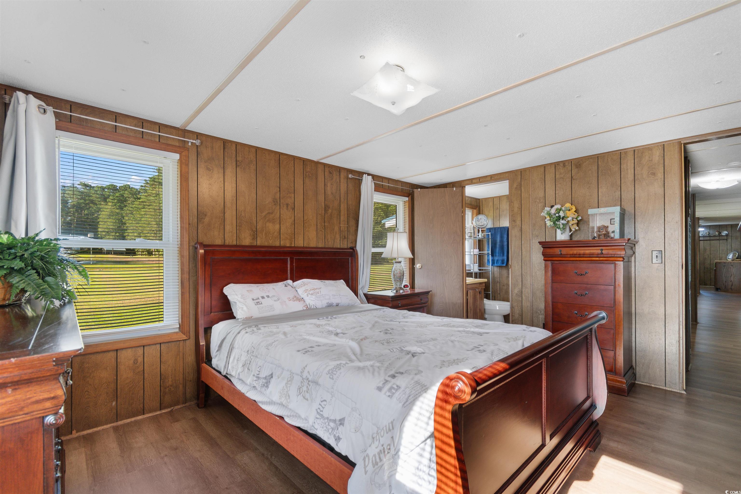 299 Williams Hill Road Hemingway, SC 29554 - Photo 25 of 40 Bedroom with wood walls, dark wood finished floors, and ensuite bath