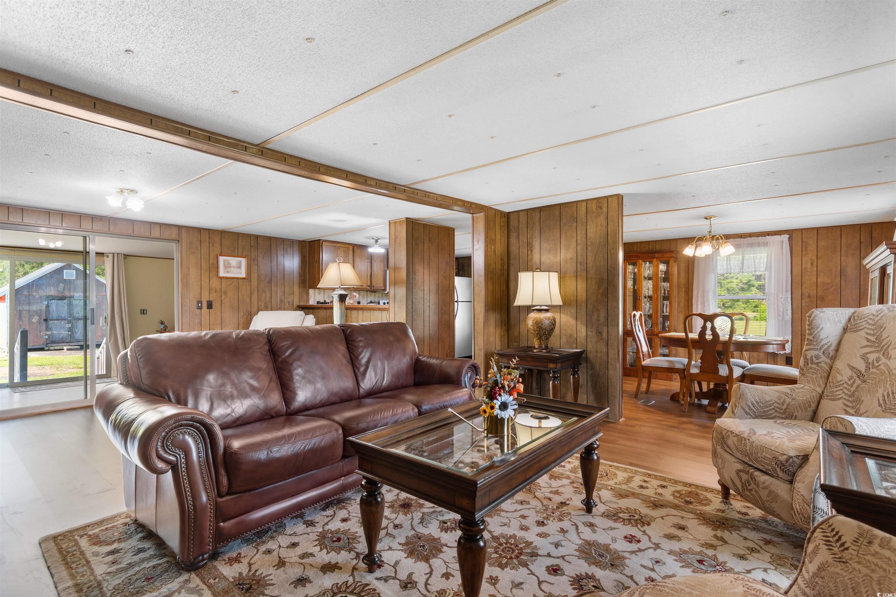 299 Williams Hill Road Hemingway, SC 29554 - Photo 3 of 40 Living room featuring beam ceiling, a chandelier, wood finished floors, and wooden walls