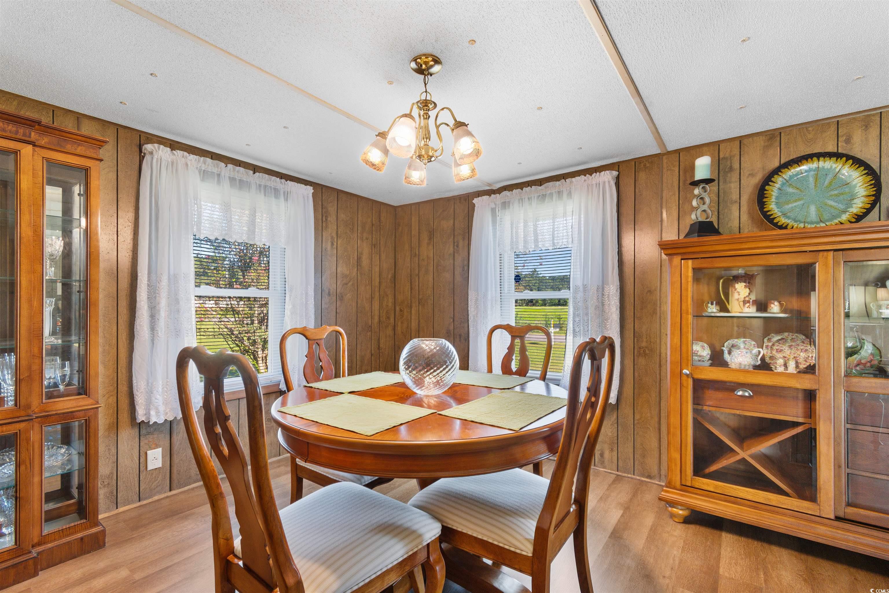 299 Williams Hill Road Hemingway, SC 29554 - Photo 8 of 40 Dining space with wooden walls, light wood-style flooring, a chandelier, and a textured ceiling