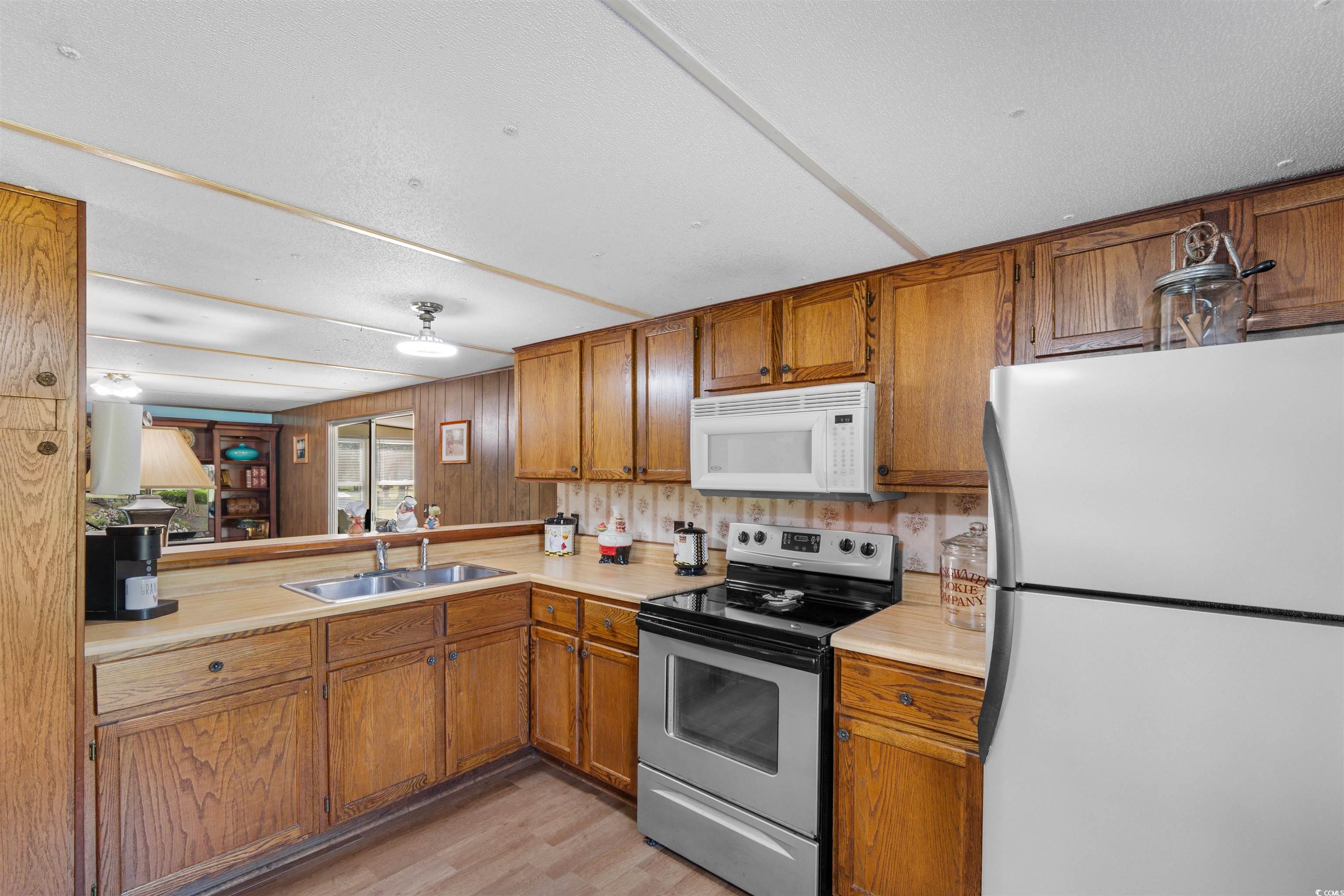 299 Williams Hill Road Hemingway, SC 29554 - Photo 9 of 40 Kitchen with white appliances, light countertops, brown cabinetry, and light wood finished floors