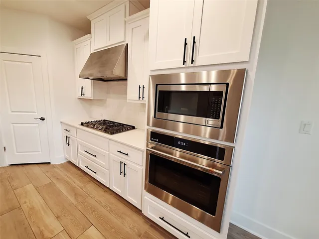 a kitchen with stainless steel appliances a stove microwave and sink