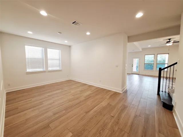 a view of empty room with wooden floor and a window