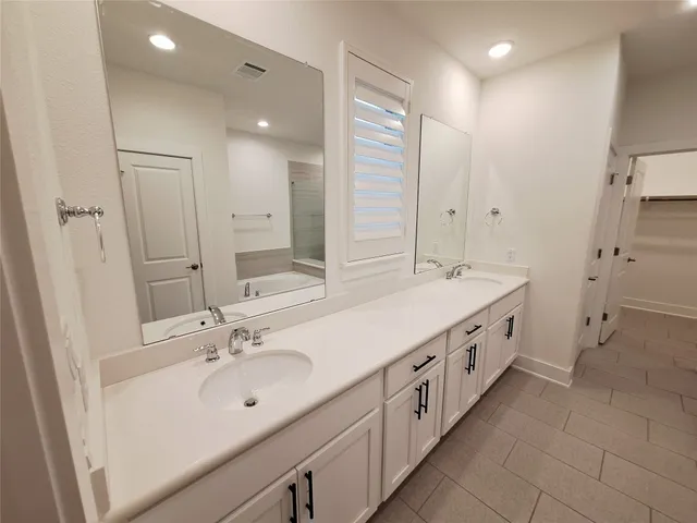 a spacious bathroom with double vanity and mirrors