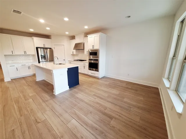 a large kitchen with kitchen island a stove a sink dishwasher and wooden floor