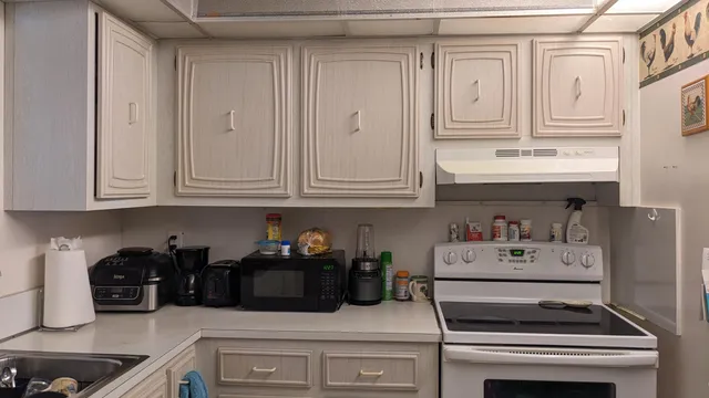 a kitchen with white cabinets and appliances