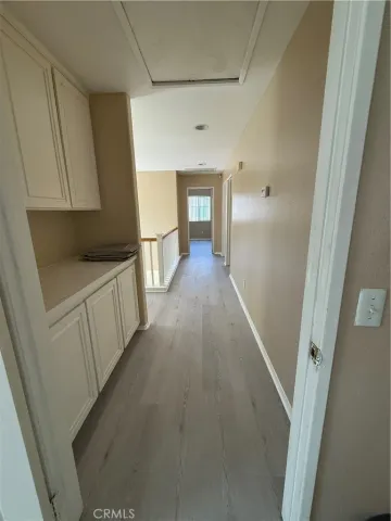 a view of a hallway to a bedroom with wooden floor and cabinet