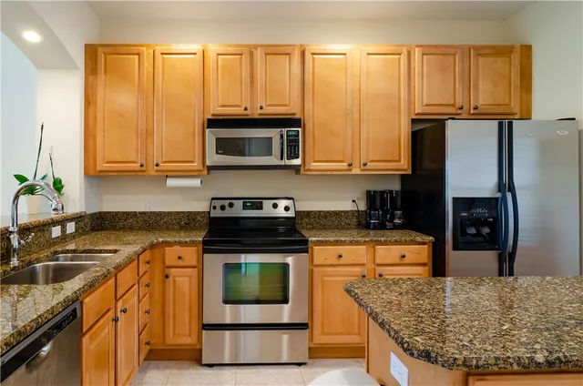 a kitchen with stainless steel appliances granite countertop a stove a sink and a microwave