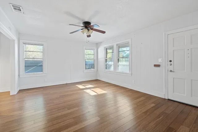 a view of empty room with wooden floor and fan