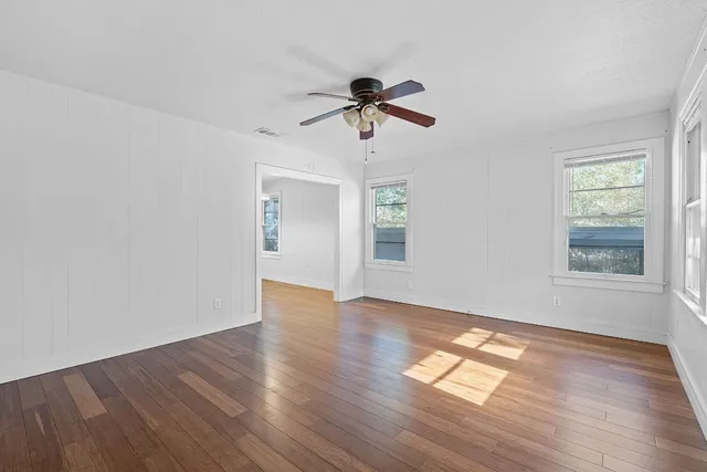 a view of empty room with wooden floor and fan