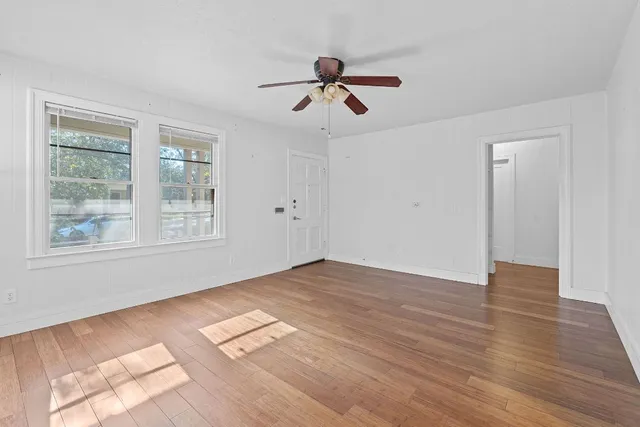 a view of empty room with wooden floor and fan