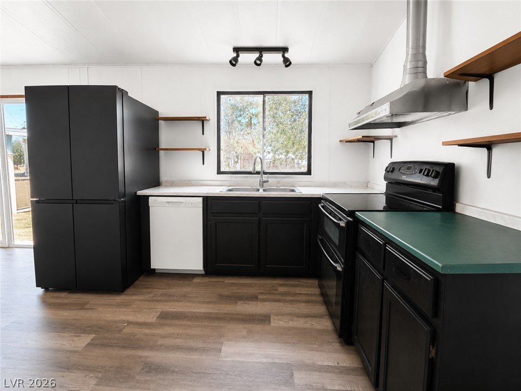 1611 West Blosser Ranch Road Pahrump, NV 89060 - Photo 8 of 25 A well-equipped kitchen features a suite of black appliances, open shelving, and rich wood flooring.