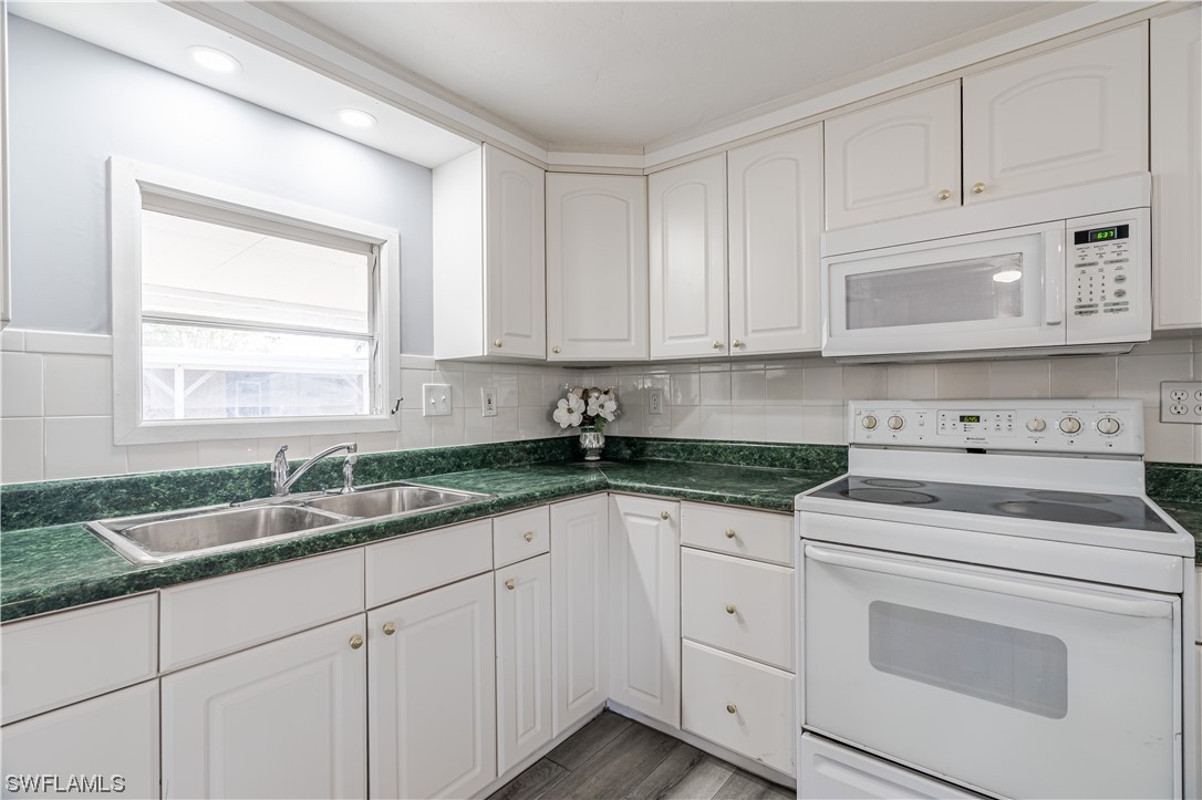 153 Cape Sable Drive Naples, FL 34104 - Photo 12 of 35 a kitchen with granite countertop white cabinets and white stainless steel appliances
