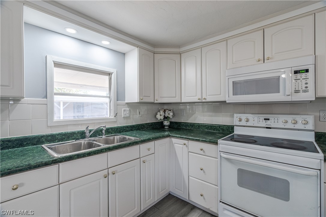153 Cape Sable Drive Naples, FL 34104 - Photo 13 of 35 a kitchen with granite countertop white cabinets and white stainless steel appliances with a sink