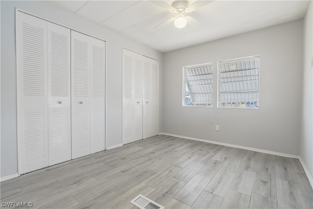 153 Cape Sable Drive Naples, FL 34104 - Photo 14 of 35 an empty room with wooden floor closet and windows