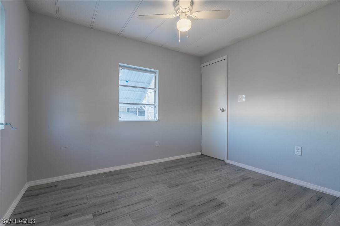 153 Cape Sable Drive Naples, FL 34104 - Photo 25 of 35 an empty room with wooden floor chandelier fan and windows