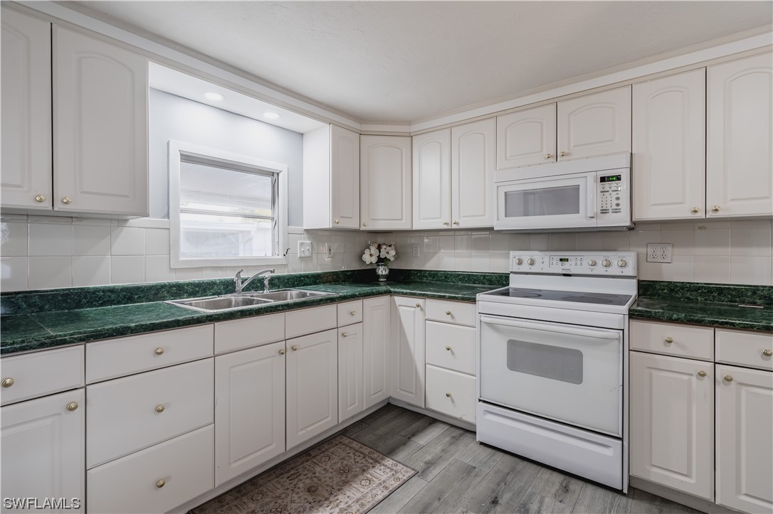 153 Cape Sable Drive Naples, FL 34104 - Photo 26 of 35 a kitchen with granite countertop white cabinets and white appliances