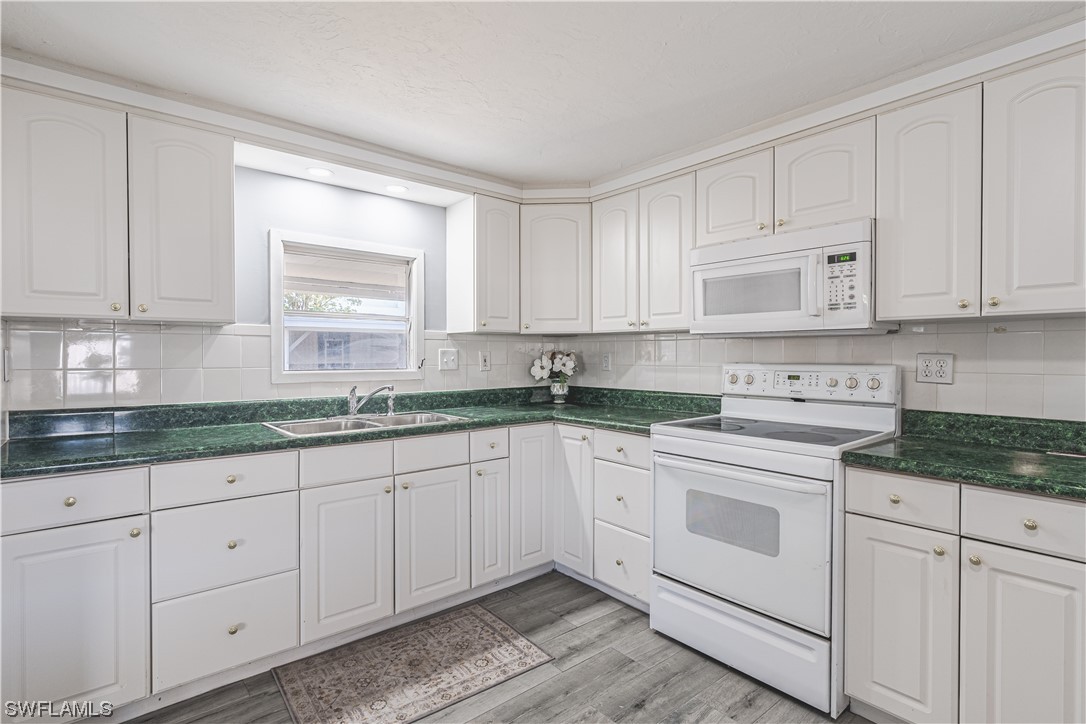 153 Cape Sable Drive Naples, FL 34104 - Photo 6 of 35 a kitchen with granite countertop white cabinets and white appliances