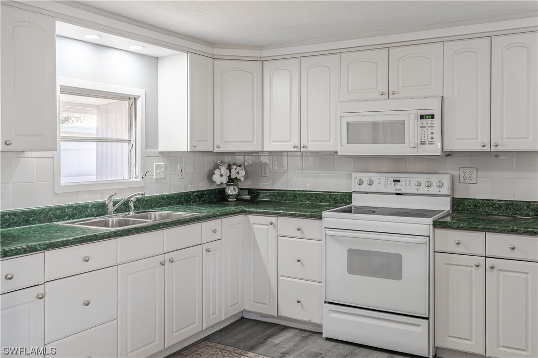 153 Cape Sable Drive Naples, FL 34104 - Photo 7 of 35 a kitchen with granite countertop white cabinets and white stainless steel appliances with a sink