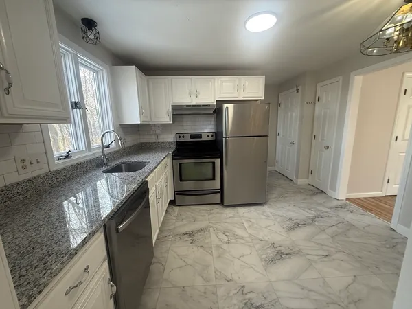 a kitchen with granite countertop a sink stove and refrigerator