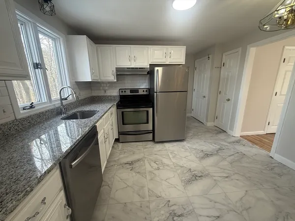 a kitchen with granite countertop a refrigerator and a sink