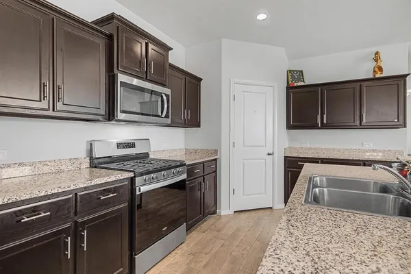 a kitchen with granite countertop wooden cabinets and a stove top oven