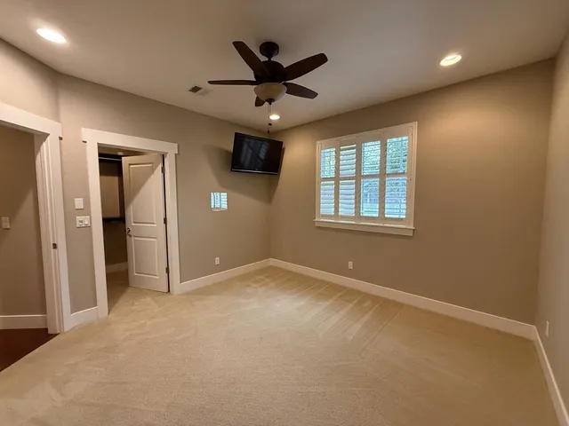an empty room with ceiling fan and windows
