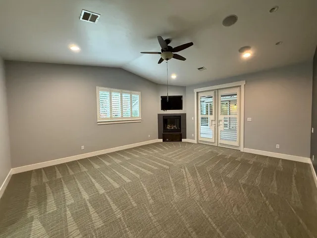 a view of an empty room with a window and a kitchen
