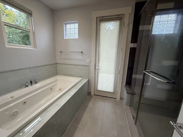 a bathroom with a tub a sink and a large mirror