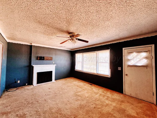 a view of an empty room with a fireplace and a window