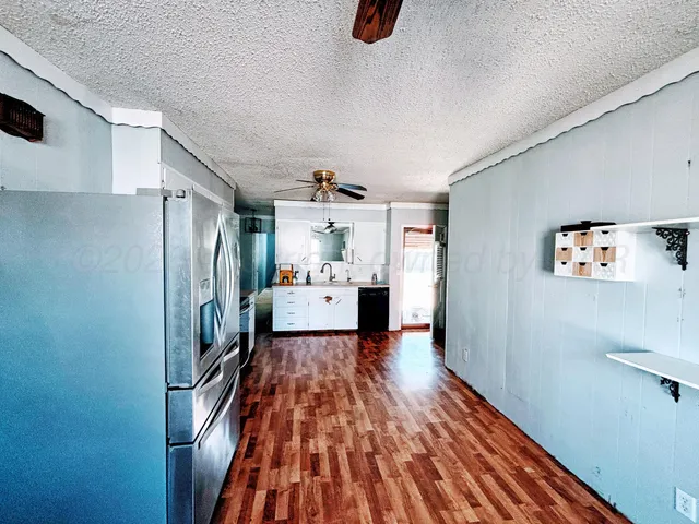 a view of a kitchen with refrigerator and wooden floor