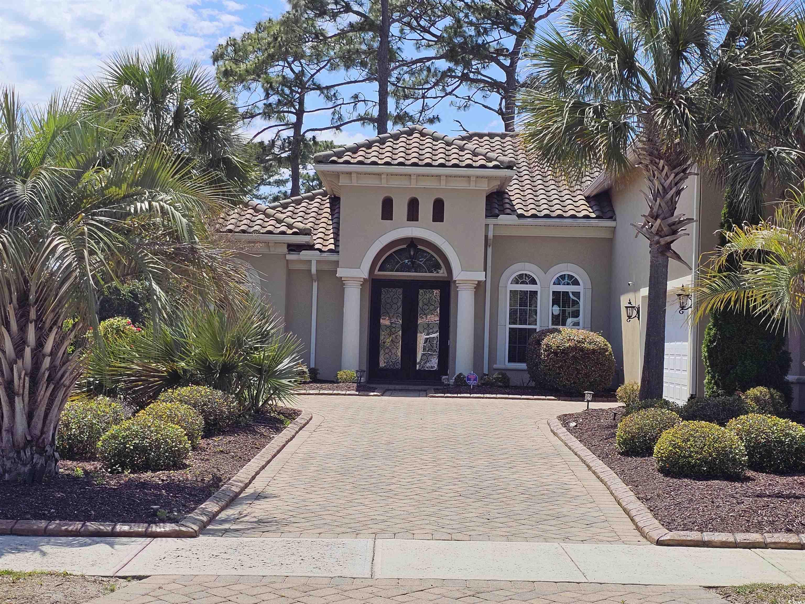 Mediterranean / spanish home featuring french doors, a tile roof, stucco siding, and decorative driveway
