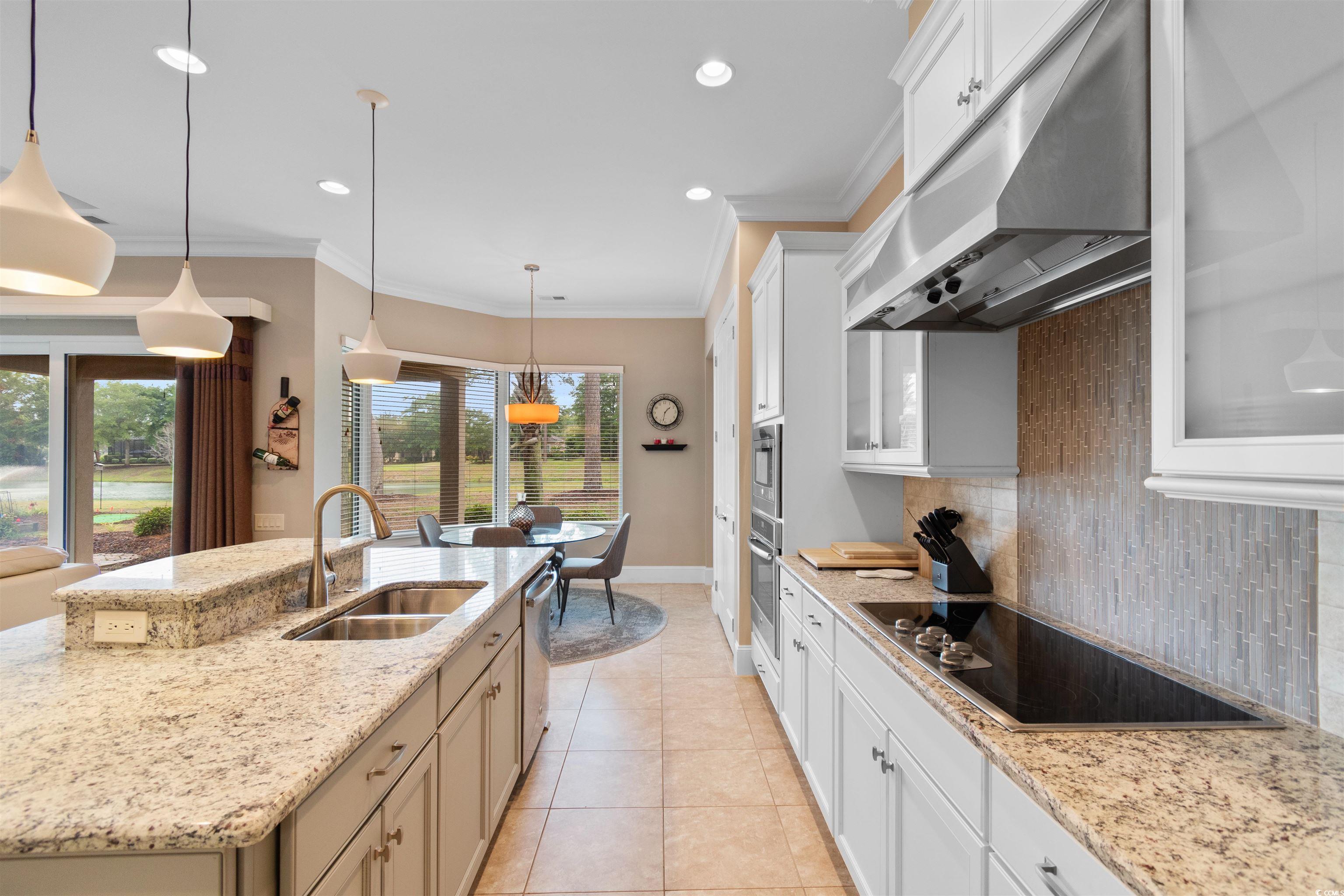 7253 Seville Drive Myrtle Beach, SC 29572 - Photo 11 of 39 Kitchen with a sink, under cabinet range hood, appliances with stainless steel finishes, decorative backsplash, and a center island with sink