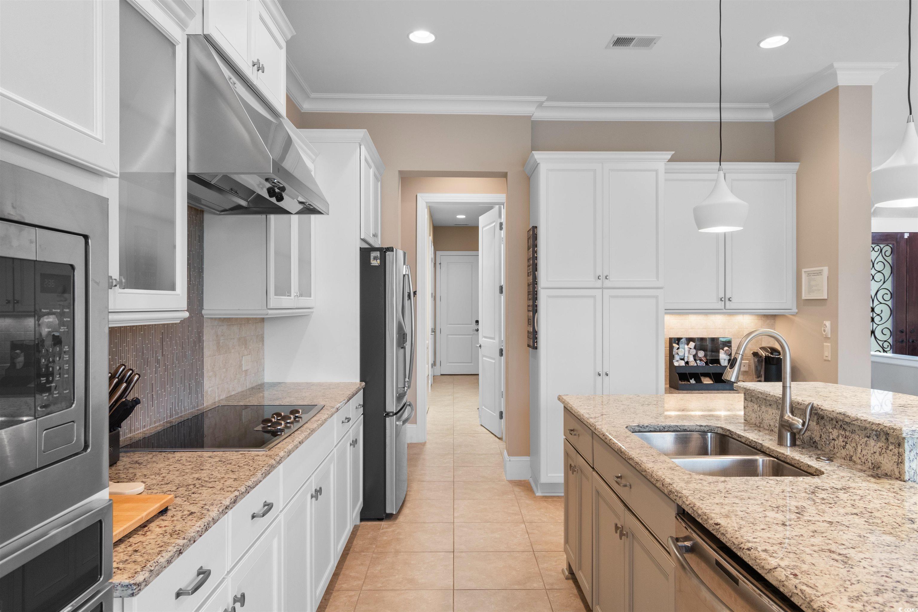 7253 Seville Drive Myrtle Beach, SC 29572 - Photo 13 of 39 Kitchen with a sink, appliances with stainless steel finishes, under cabinet range hood, white cabinets, and decorative backsplash