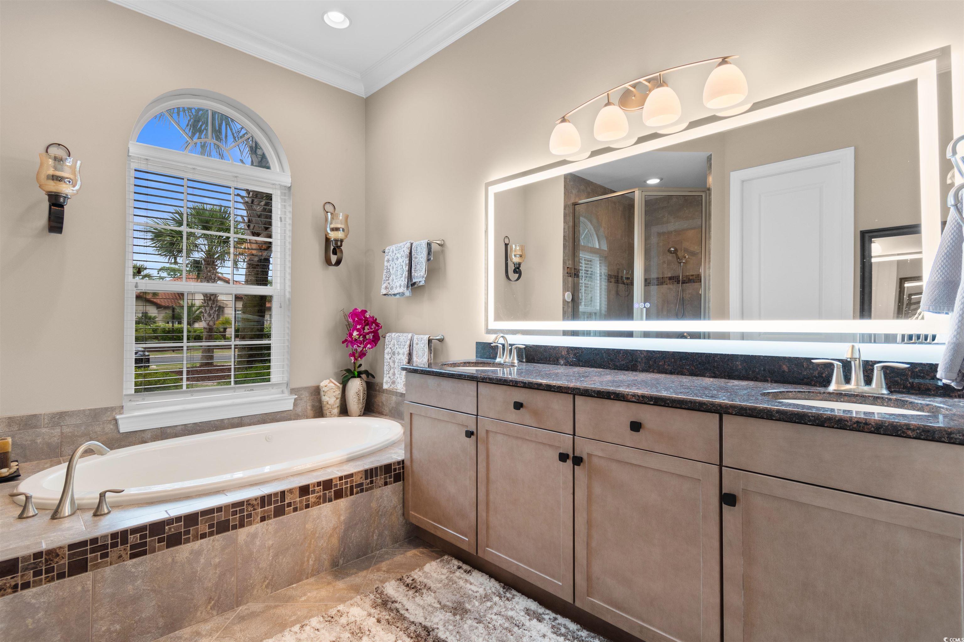 7253 Seville Drive Myrtle Beach, SC 29572 - Photo 19 of 39 Full bath with healthy amount of natural light, a stall shower, crown molding, a bath, and double vanity