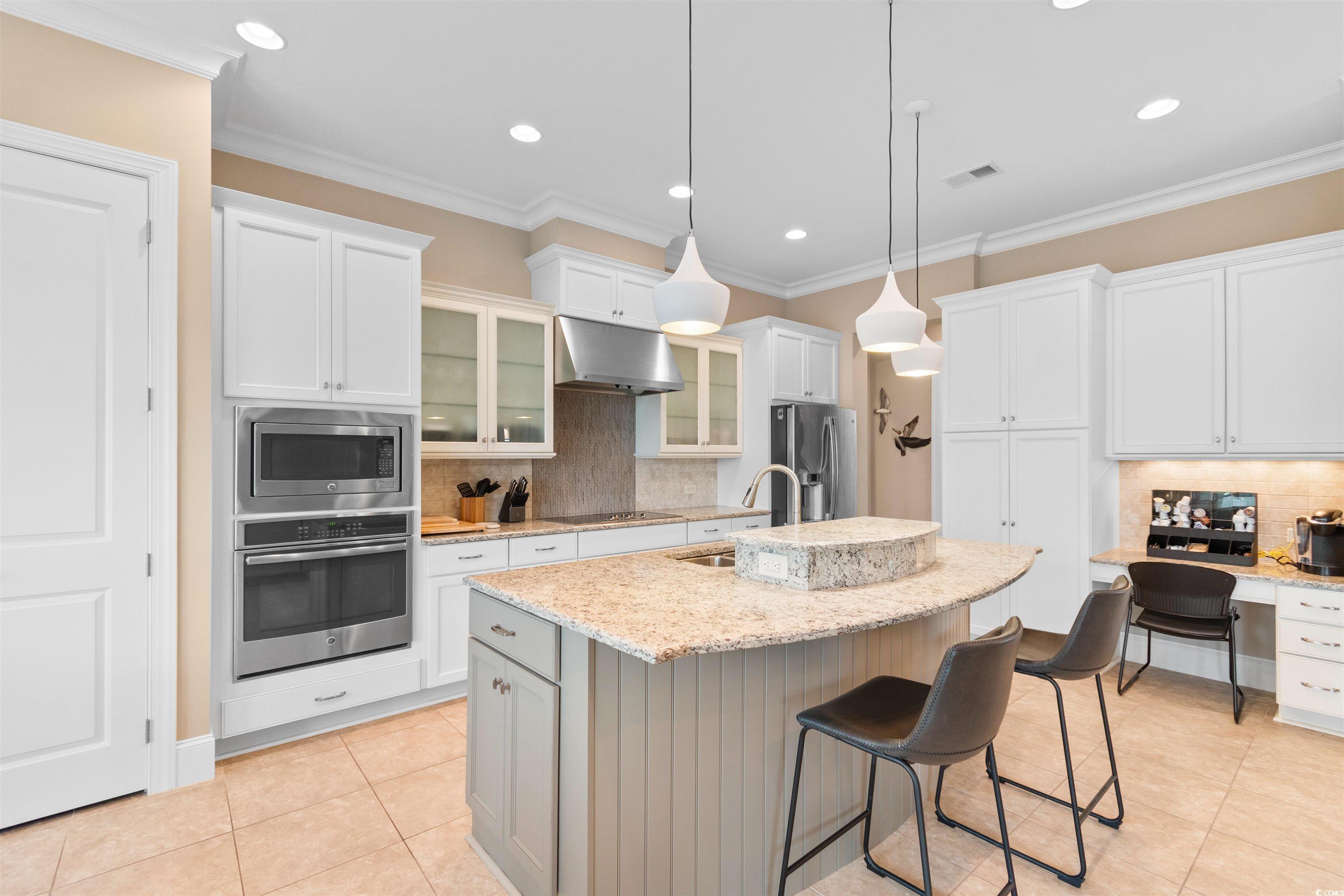 7253 Seville Drive Myrtle Beach, SC 29572 - Photo 9 of 39 Kitchen featuring appliances with stainless steel finishes, under cabinet range hood, a sink, light tile patterned floors, and backsplash