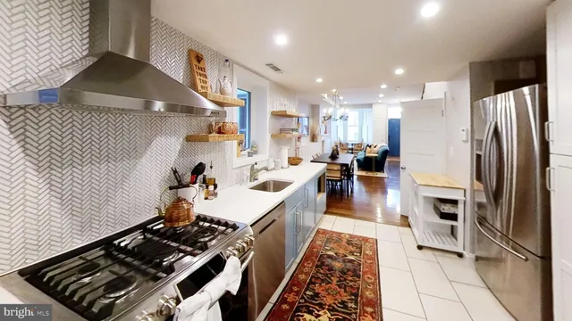 a kitchen with stainless steel appliances granite countertop a stove a sink dishwasher and a refrigerator with wooden floor