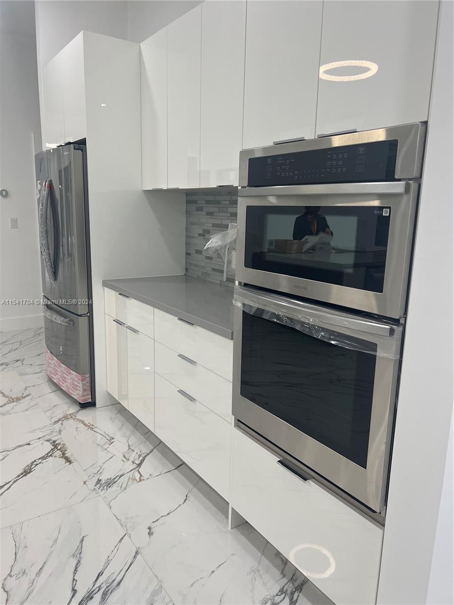 5455 Southwest 60th Court Miami, FL 33155 - Photo 13 of 68 a kitchen with granite countertop white cabinets and stainless steel appliances