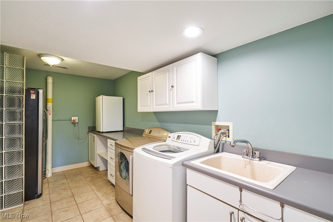 4535 Pinewood Path Akron, OH 44321 - Photo 18 of 27 Washroom with washing machine and clothes dryer, light tile patterned floors, and cabinet space
