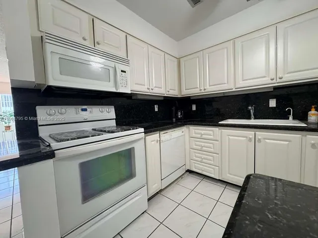 a kitchen with white cabinets and white appliances