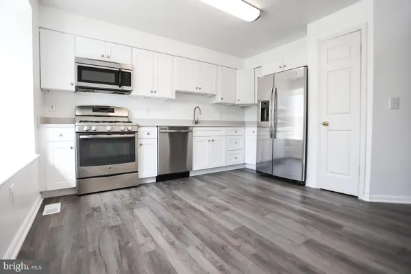 a kitchen with stainless steel appliances a stove a microwave and white cabinets
