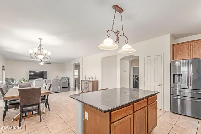 a kitchen with stainless steel appliances kitchen island granite countertop a table chairs and a refrigerator