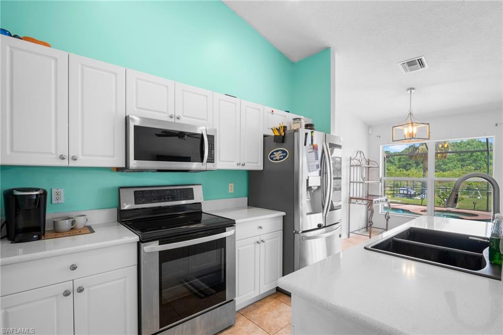 15601 Cemetery Road Fort Myers, FL 33905 - Photo 4 of 20 Kitchen with stainless steel appliances, a sink, white cabinetry, hanging light fixtures, and light countertops