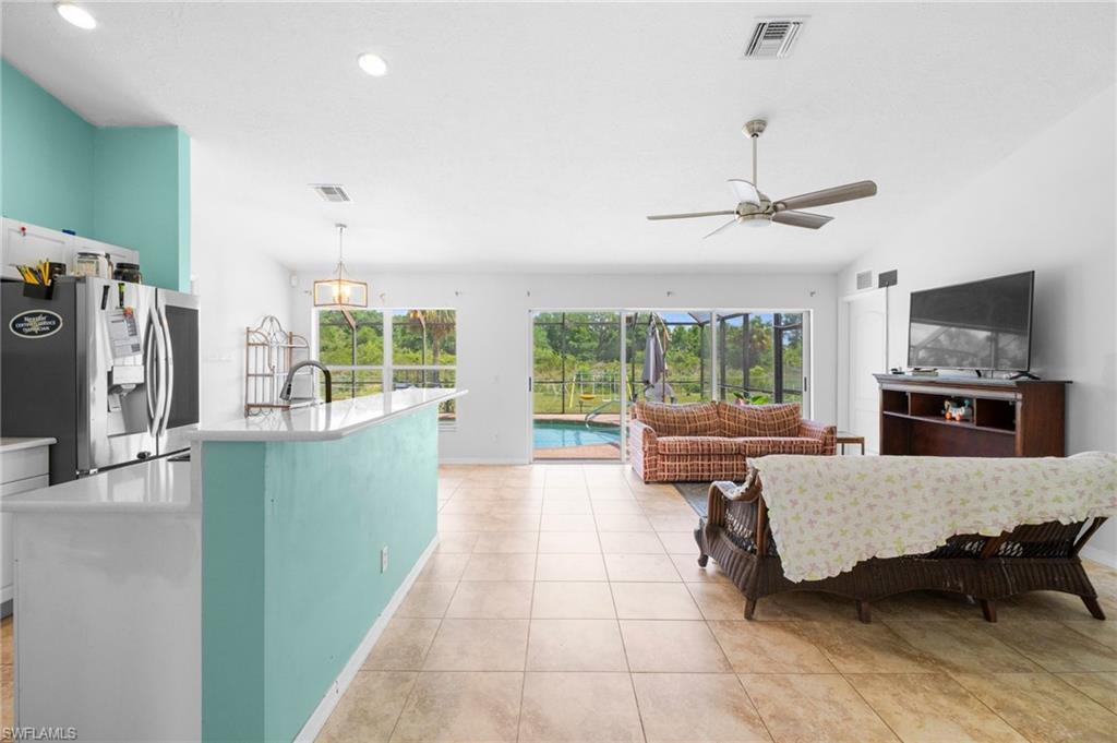 15601 Cemetery Road Fort Myers, FL 33905 - Photo 6 of 20 Kitchen featuring stainless steel fridge with ice dispenser, open floor plan, a ceiling fan, light countertops, and a kitchen island with sink