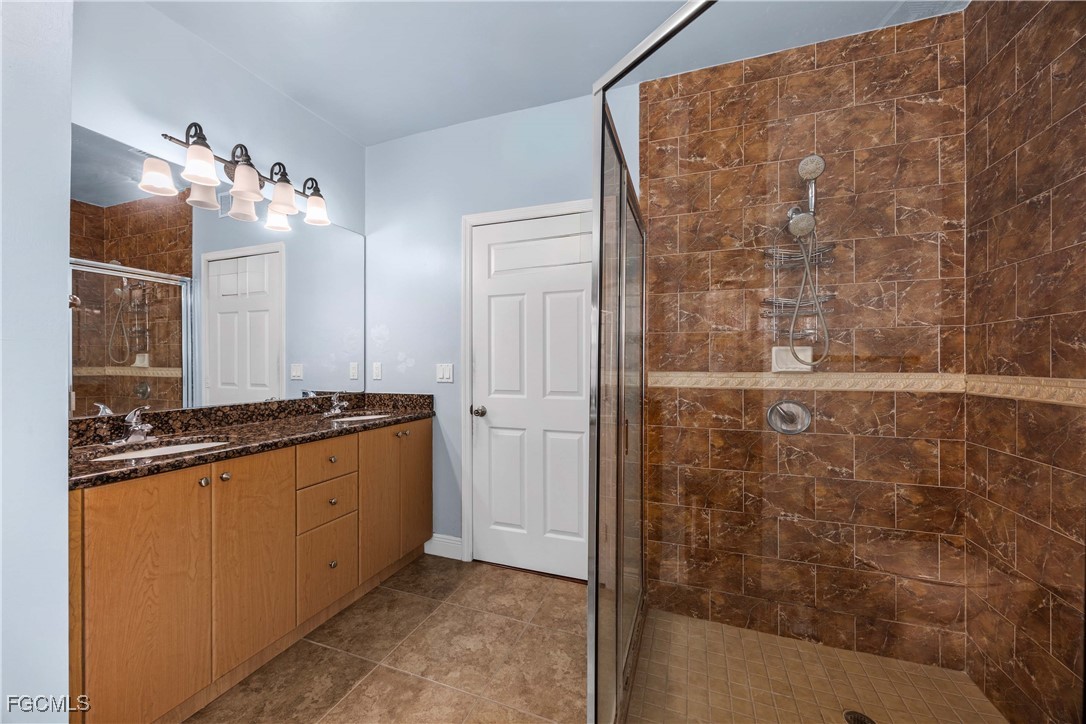 360 18th Street Northeast Naples, FL 34120 - Photo 18 of 37 a bathroom with a granite countertop sink a mirror and shower
