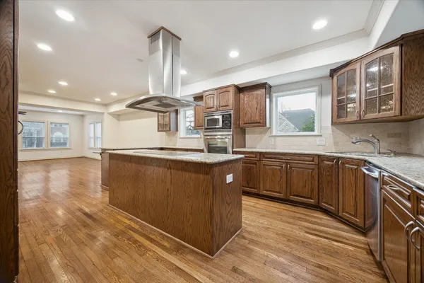 a kitchen with stainless steel appliances granite countertop a sink a stove and a wooden floors