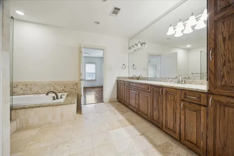 a spacious bathroom with a tub sink and mirror