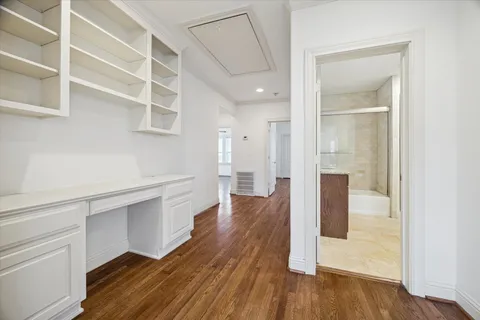 a hallway with wooden floor closet and windows