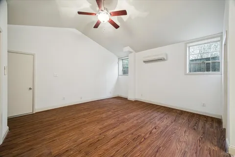 an empty room with wooden floor fan and windows